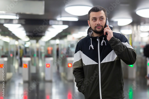 Man in jacket with a mobile phone near turnstile in the subway