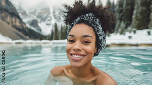 A smiling woman enjoying a hot bath in a pool with a snowy mountain background, suggesting a winter retreat or spa concept with steam coming off the water. Ai generative © ImageFlow