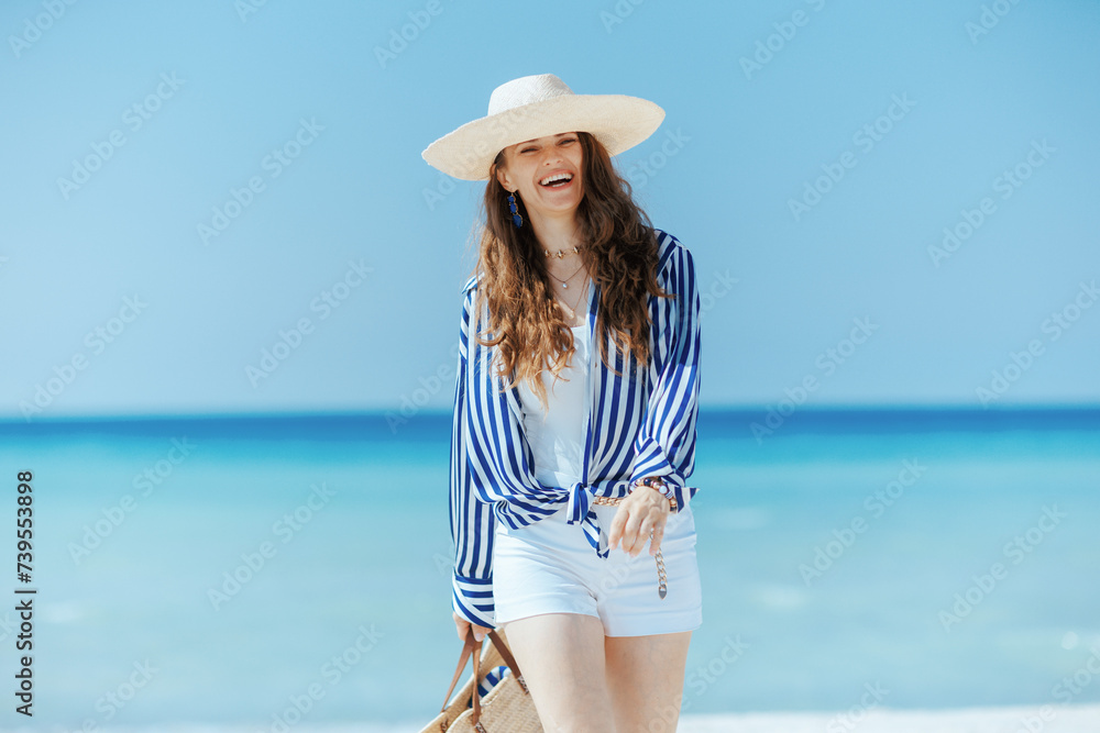 smiling stylish female on beach with straw hat