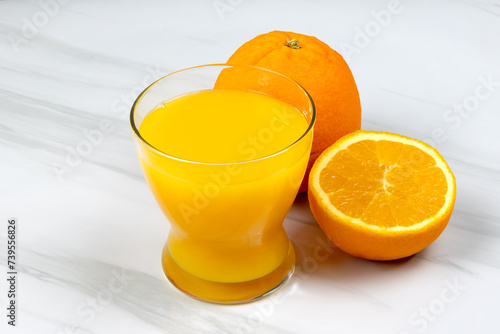verre de jus d'orange et oranges fraiches sur une table 