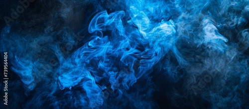 Ethereal blue smoke swirls on dark black background, abstract and mysterious atmosphere