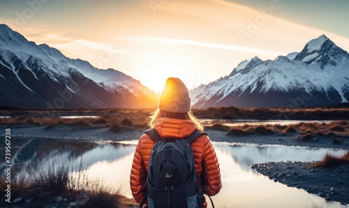 Winter Wonderland Expedition: A Happy Tourist Woman, Back View, Immerses Herself in the Tranquility of a Glacier Lake, Aoraki/Mount Cook, and the Southern Alps under the Majestic Sunset Sky in Winter photo