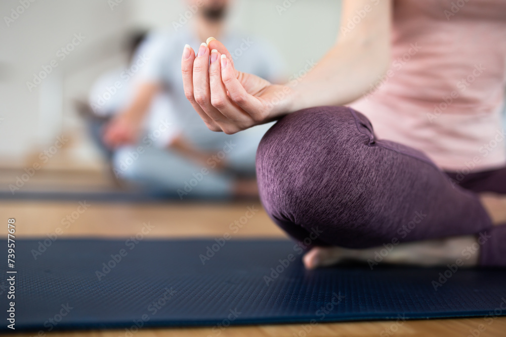 Hand of woman making mudra, lotus pose practicing. Meditation during group yoga training.