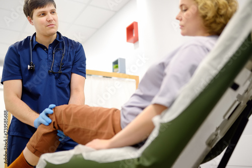 Woman at an appointment with rheumatologist talks about pain symptom of knee joint. Orthopedic doctor examines a patient. photo