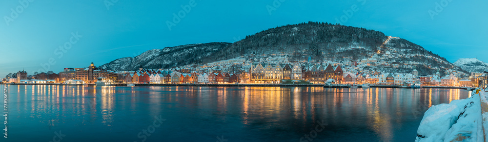 Fototapeta premium Beautiful evening panorama of Bergen waterfront, Bryggen area. Magical wide cityscape at night, covering the whole bay of Bergen. Long exposure, lights on houses are lit.