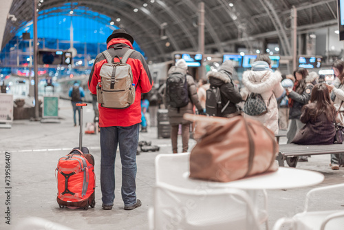 Obraz na płótnie Unknown person with red jacket, backpack and a bag is waiting for a departure of a train in Bergen train station. Magnificent metal structure as a roof of a station. w salonie