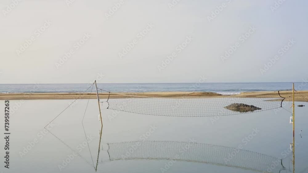 Beach volleyball net on the beach drowned in water and surrounded by sand dunes facing the ocean Beach volleyball net on the beach drowned in water and surrounded by sand dunes facing the ocean