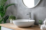 Minimalist modern Scandinavian bathroom with white washbasin wooden countertop and stylish grey wall Round mirror faucet copy space nobody