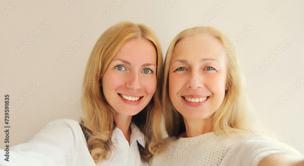 Portrait of happy smiling middle aged mother and adult daughter taking selfie with phone together Portrait of happy smiling middle aged mother and adult daughter taking selfie with phone together