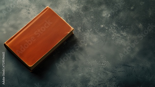 A closed orange book on a textured dark background