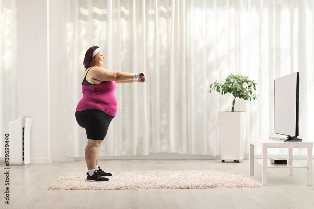 Full length profile shot of a plus size woman exercising with dumbbells Full length profile shot of a plus size woman exercising with dumbbells