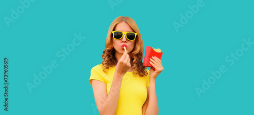 Portrait of stylish young woman eating french fries, fried potatoes fast food