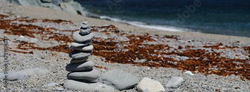 Panorama image of a Rock Cairn on the beach at the Cap-des-Rosiers Lighthouse at La Cote-de-Gaspe, Gaspe Peninsula on the Gulf of St. Lawrence Quebec Canada photo