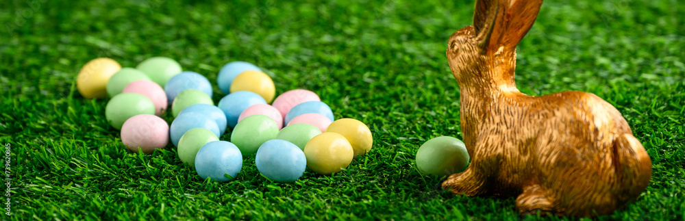 Happy Easter, gold easter bunny and pastel colored candy coated Easter eggs on artificial green grass
Happy Easter, gold easter bunny and pastel colored candy coated Easter eggs on artificial green grass