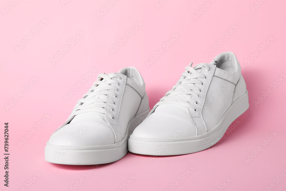 Pair of stylish white sneakers on pink background