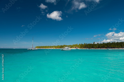 Seascape with crystal clear shallow turquoise ocean water, deep blue sky and white yachts and boats on the water surface. Saona Island, Dominican Republic. Wide angle shot.
