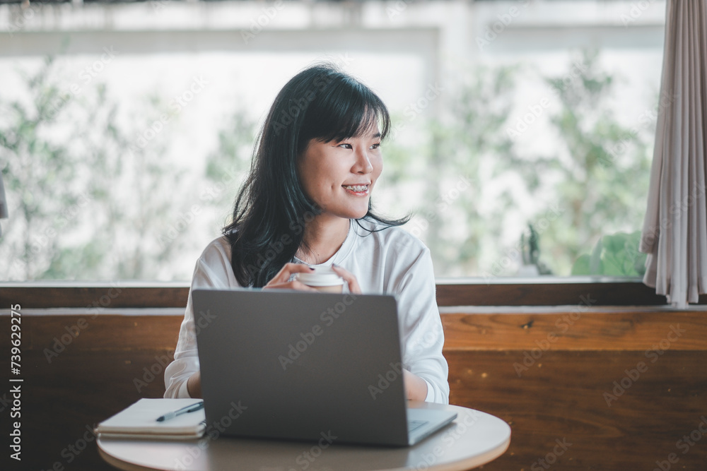 Business freelance concept, A hopeful woman engaging with her laptop in a spacious cafe, with the comfort of natural light from a large window. Business freelance concept, A hopeful woman engaging with her laptop in a spacious cafe, with the comfort of natural light from a large window.