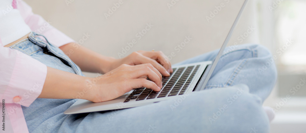 Fototapeta premium Closeup hands business woman work from home with laptop computer online to internet on sofa in living room, freelance girl using notebook sitting on couch with comfort and relax, lifestyles concept.