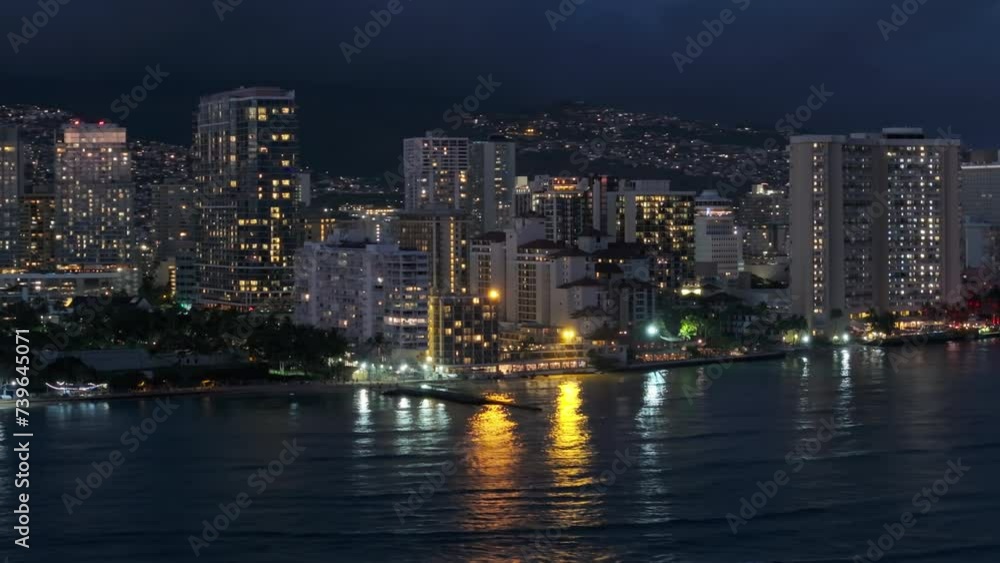 Scenic downtown on tropical island Oahu 4K. Scenic view over Waikiki beach at night. Beautiful Honolulu modern buildings illuminated at night. Drone shot from water of Hawaii largest city after dark Scenic downtown on tropical island Oahu 4K. Scenic view over Waikiki beach at night. Beautiful Honolulu modern buildings illuminated at night. Drone shot from water of Hawaii largest city after dark