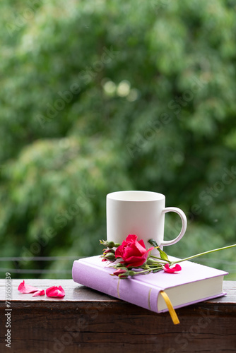 A rose flower, a book and a cup of coffee. Beautiful summer still life on the windowsill