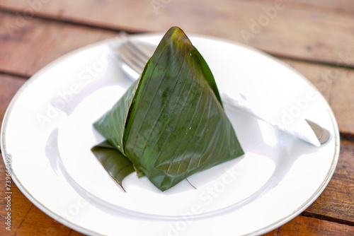 Nasi Liwet Sunda is a traditional Indonesian rice dish of white rice cooked with spices still wrapped in banana leaves served on a white plate.