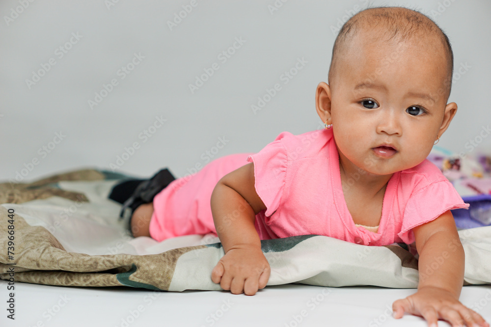 portrait of a cute asian baby girl wearing a pink outfit trying to crawl on a white background portrait of a cute asian baby girl wearing a pink outfit trying to crawl on a white background