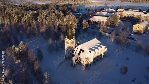 Arvidsjaur Church Covered With Snow On Sunny Winter Day In Arvidsjaur, Sweden. aerial pullback photo