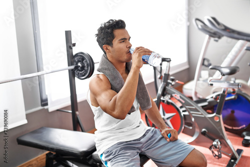 Fotografie Gym, fitness and man drinking water for training, wellness or exercise recovery, break or resting