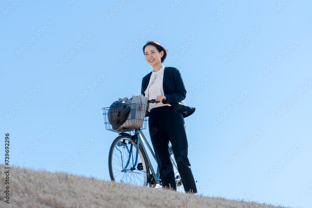 屋外で自転車をおすスーツを着た女性