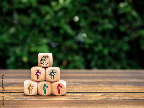 Cooperation icon on top of wood cubes pyramid shape with human holding leaf symbols. Green life society community members sustainability, conserve resources and environmental responsibility concepts.