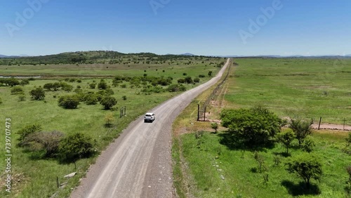 White SUV drives through a gate in KwaZulu Natal, South Africa aerial. off road driving in African plains photo