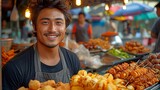 A young man from the area stands behind his street food kiosk and beams. Thai food is sold by a male street seller at the market.