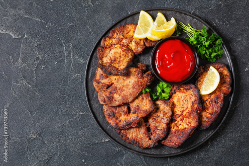 fried juicy pork steaks with ketchup on plate