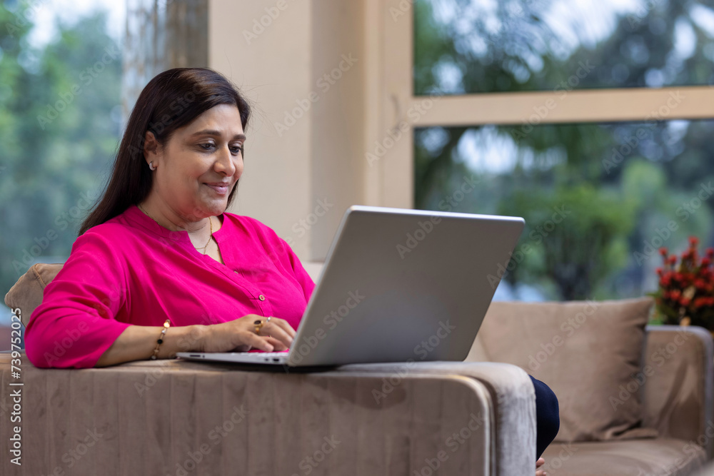 Relaxed woman using laptop on sofa at home Relaxed woman using laptop on sofa at home