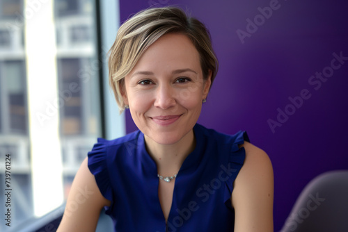 Free Download Executive woman in blue blouse with short blonde hair looking at camera against office window - GFXLoad