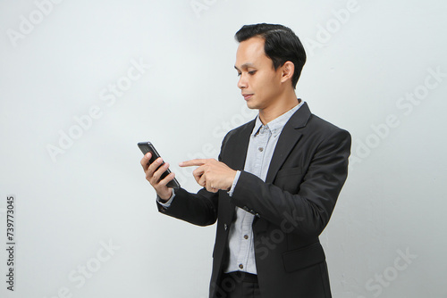 happy asian indonesian business man in suit holding smart phone on isolated background