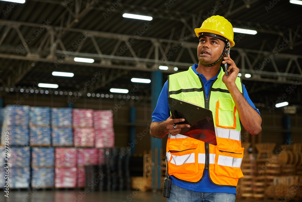 factory worker holding a clipboard and talking on smartphone to customer in the warehouse factory factory worker holding a clipboard and talking on smartphone to customer in the warehouse factory