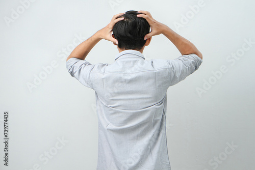 back view of asian indonesian man with hand grab his head showing stressful confused gesture. isolated background