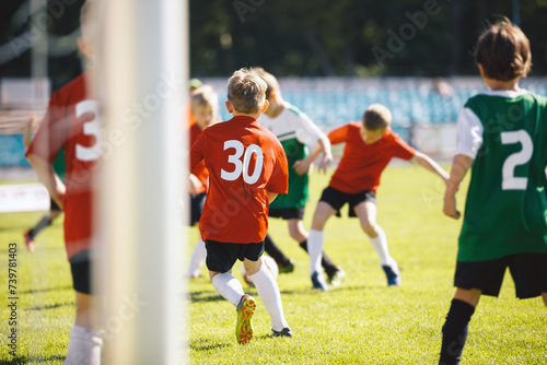 Group of School Boys Play Soccer Football Match With Friends. Youth Professionals Soccer Kids Kicking Ball on Grass Pitch. CHildren in Red an Green Jersey Shirts With White Numbers on Back