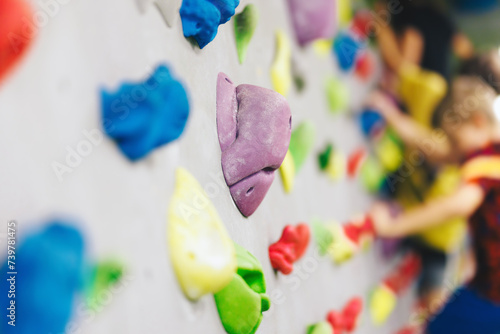 Bouldering Climbing Wall Holds Kids Playing in Background. Indoor Climbing Equipment