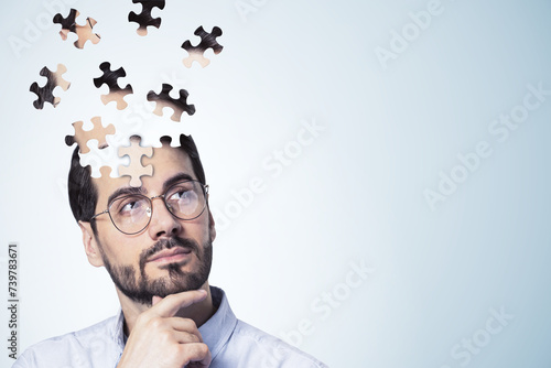 Puzzle headed thoughtful businessman portrait on light background with mock up place. Solution, decision and brainstorm concept.