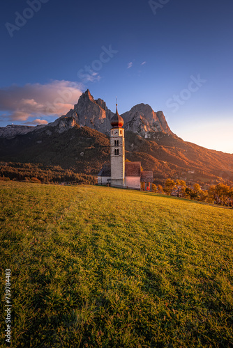 Seis am Schlern, Italy - Famous St. Valentin Church and Mount Sciliar mountain at background. Idyllic mountain scenery in the Italian Dolomites with blue sky and and warm sunlight at South Tyrol