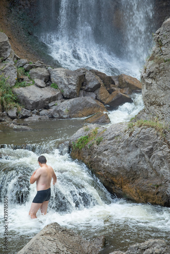 Back view of man in small waterfall.