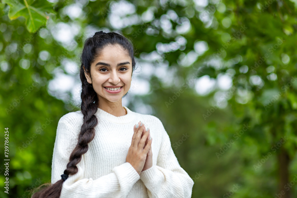 Portrait of an Indian beautiful smiling woman standing in a park with her arms folded and looking at the camera in casual sportswear. Close-up photo Portrait of an Indian beautiful smiling woman standing in a park with her arms folded and looking at the camera in casual sportswear. Close-up photo