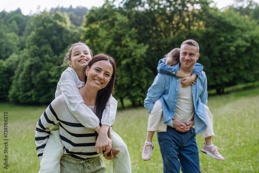 Portrait of beautiful family, parents piggibacking two daughters, having fun in nature. Portrait of beautiful family, parents piggibacking two daughters, having fun in nature.