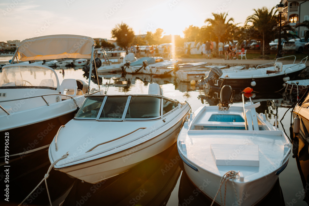 Obraz premium Small boats on calm water, moored in the harbor during sunset.