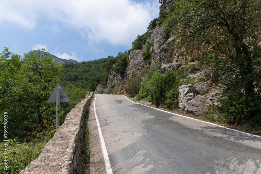 Obraz premium A paved road along rocky mountains with a dangerous curve. Landscape.