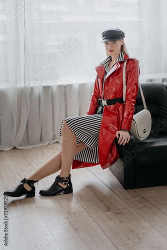 Beautiful girl in a red leather coat posing indoors