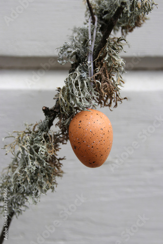 osterdeko - gesprenkeltes ei an einem zweig mit flechten