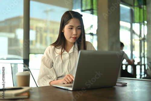 Concentrated businesswoman working with laptop at desk in coffee shop